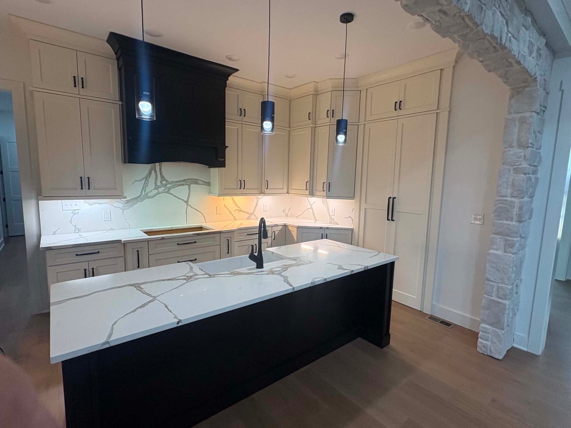 Cream perimeter cabinetry and a black waterfall island installed by Howard's Cabinet Installation in a Central Kentucky kitchen